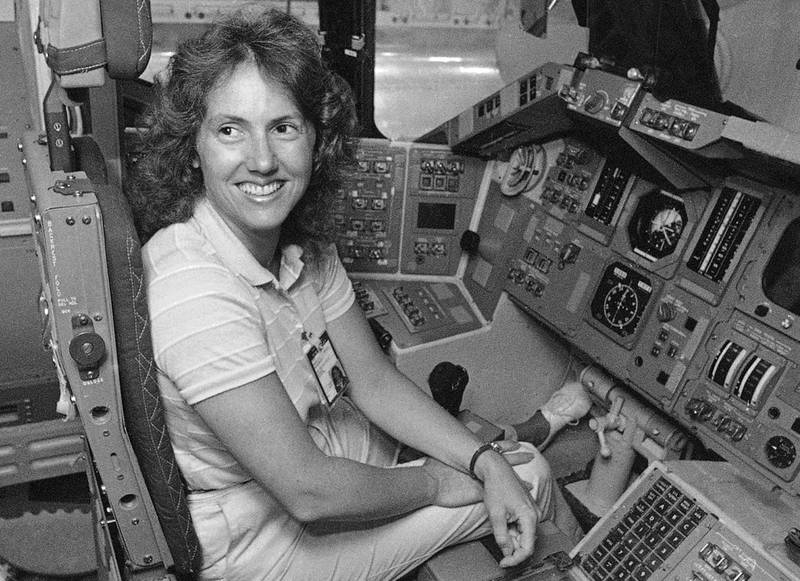 FILE - In this Sept. 13, 1985 file photo, Christa McAuliffe tries out the commander's seat on the flight deck of a shuttle simulator at the Johnson Space Center in Houston, Texas. Thirty-two years after the Challenger disaster, a pair of teachers turned astronauts on the International Space Station will pay tribute to McAuliffe by carrying out her science classes. (AP Photo)