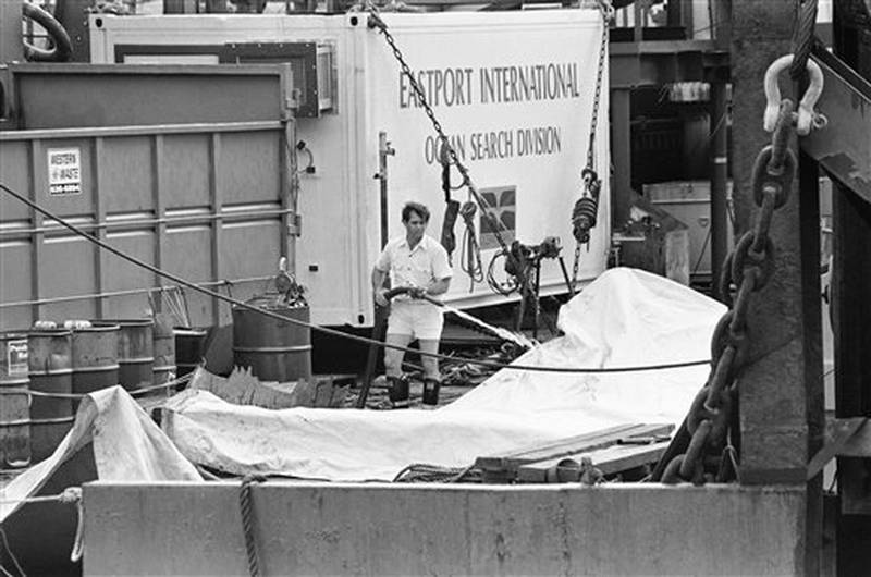A Morton Thiokol worker washes a tarp covering a portion of a solid rocket booster that was retrieved from the floor of the Atlantic by the salvage ship, the Stena Workhorse, Wednesday, March 20, 1986, Port Canaveral, Fla. The segment might provide clues to NASA scientists as to the cause of the explosion of the Space Shuttle Challenger if the segment proves to be right hand booster. (AP Photo/Thom Baur)