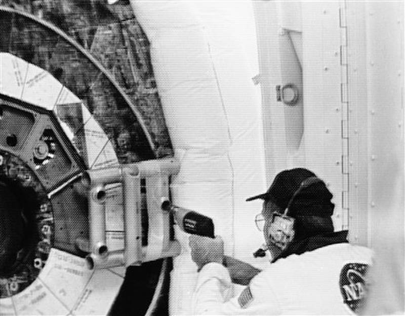 A technician uses a drill as he tries to remove a screw holding the handle to the Space Shuttle Challenger hatch, Jan. 27, 1986. The handle problem was causing a delay in launching the "Teacher in Space" flight. (AP Photo/Ed Kolenovsky)
