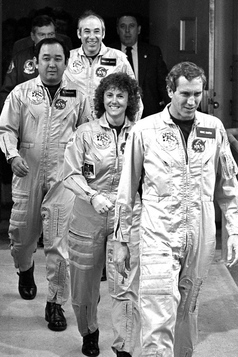 FILE - In this Jan. 28, 1986 file photo, four crew members of the space shuttle Challenger walk from their quarters at Kennedy Space Center in Florida, en route to the launch pad. From foreground are pilot Mike Smith, school teacher Christa McAuliffe, mission specialist Ellison Onizuka and payload specialist Gregory Jarvis. Thirty-two years after the Challenger disaster, a pair of teachers turned astronauts on the International Space Station will pay tribute to McAuliffe by carrying out her science classes. (AP Photo/Steve Helber)