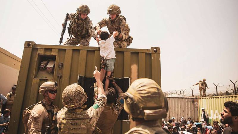 UK coalition forces, Turkish coalition forces, and U.S. Marines assist a child during an evacuation at Hamid Karzai International Airport, Kabul, Afghanistan, Aug. 20, 2021.